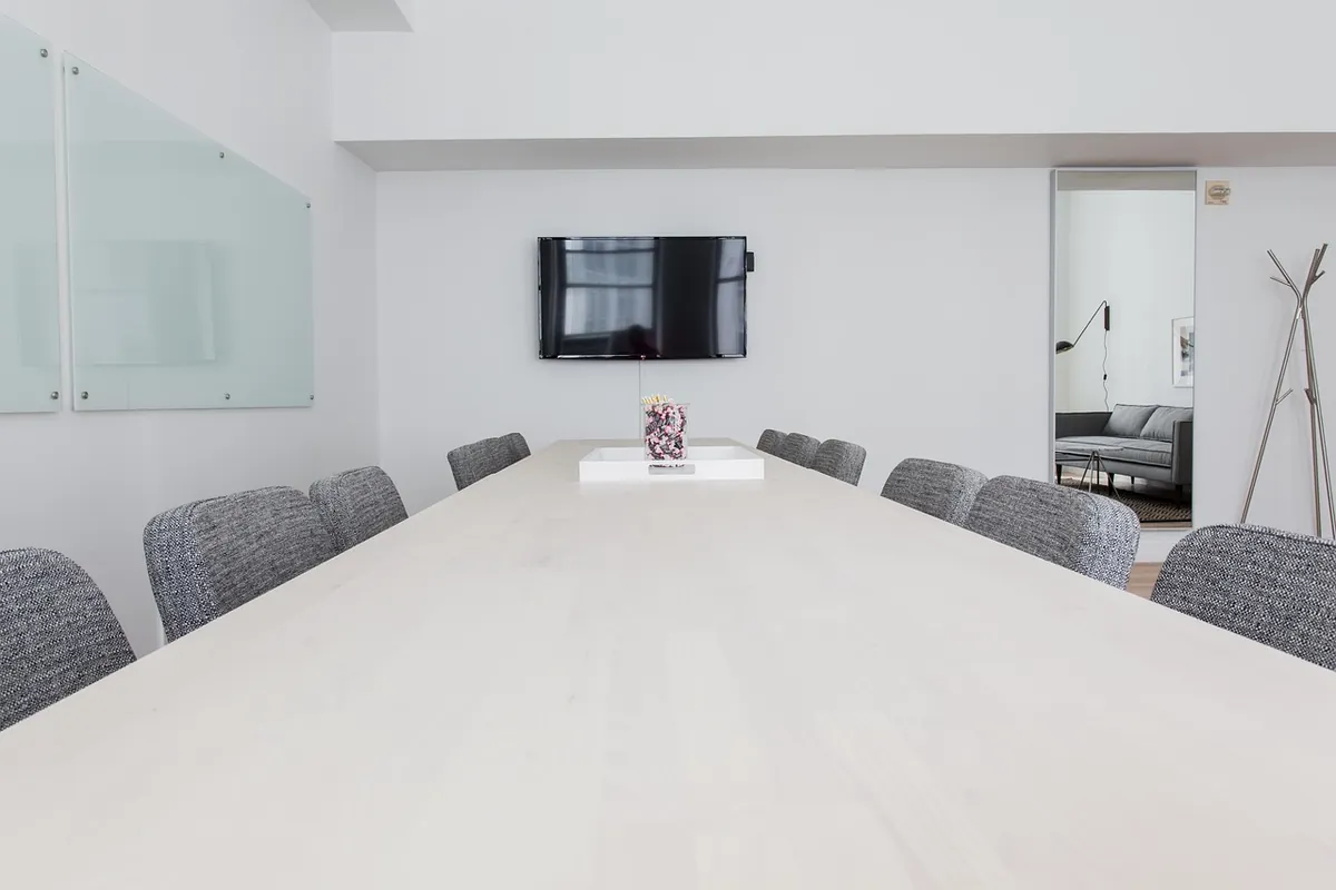 Sala riunioni vuota con tavolo chiaro e sedie grigie